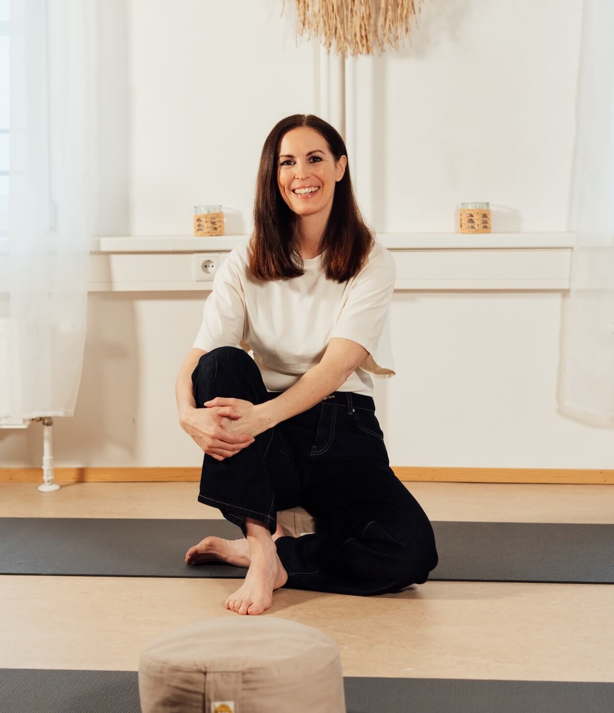 Christine Cottogni lächelnd und barfuß auf einer Yogamatte – Expertin für die Verbindung von Leistungswelt und tiefer Nervensystemregulation